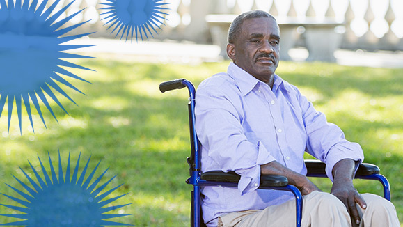 A man in a wheelchair sits in a park.