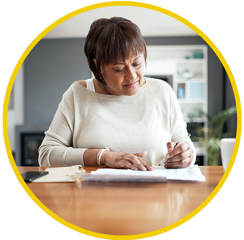 A woman sits at a dining room table, looking over her social security benefit papers.