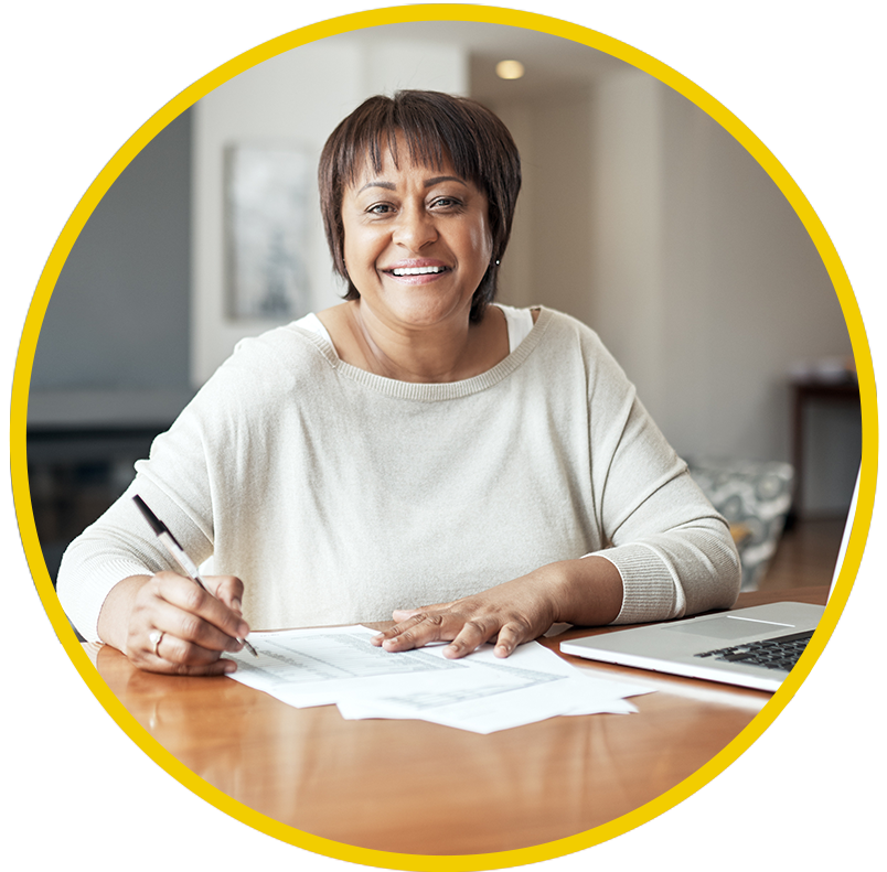 A woman sits at a dining room table looking over her social security benefits package