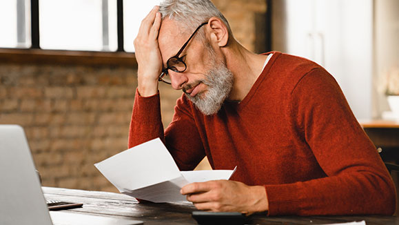 An upset man looking at a disability denial letter.