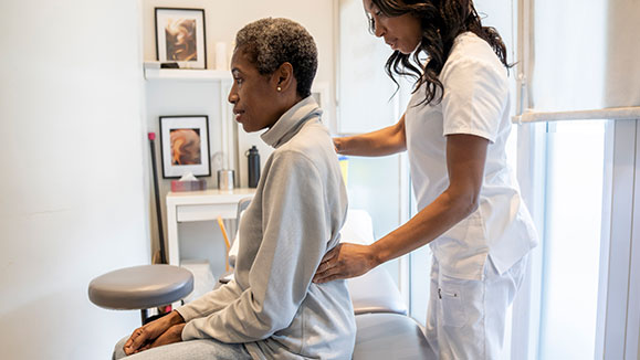A woman with back pain being checked out by a doctor.